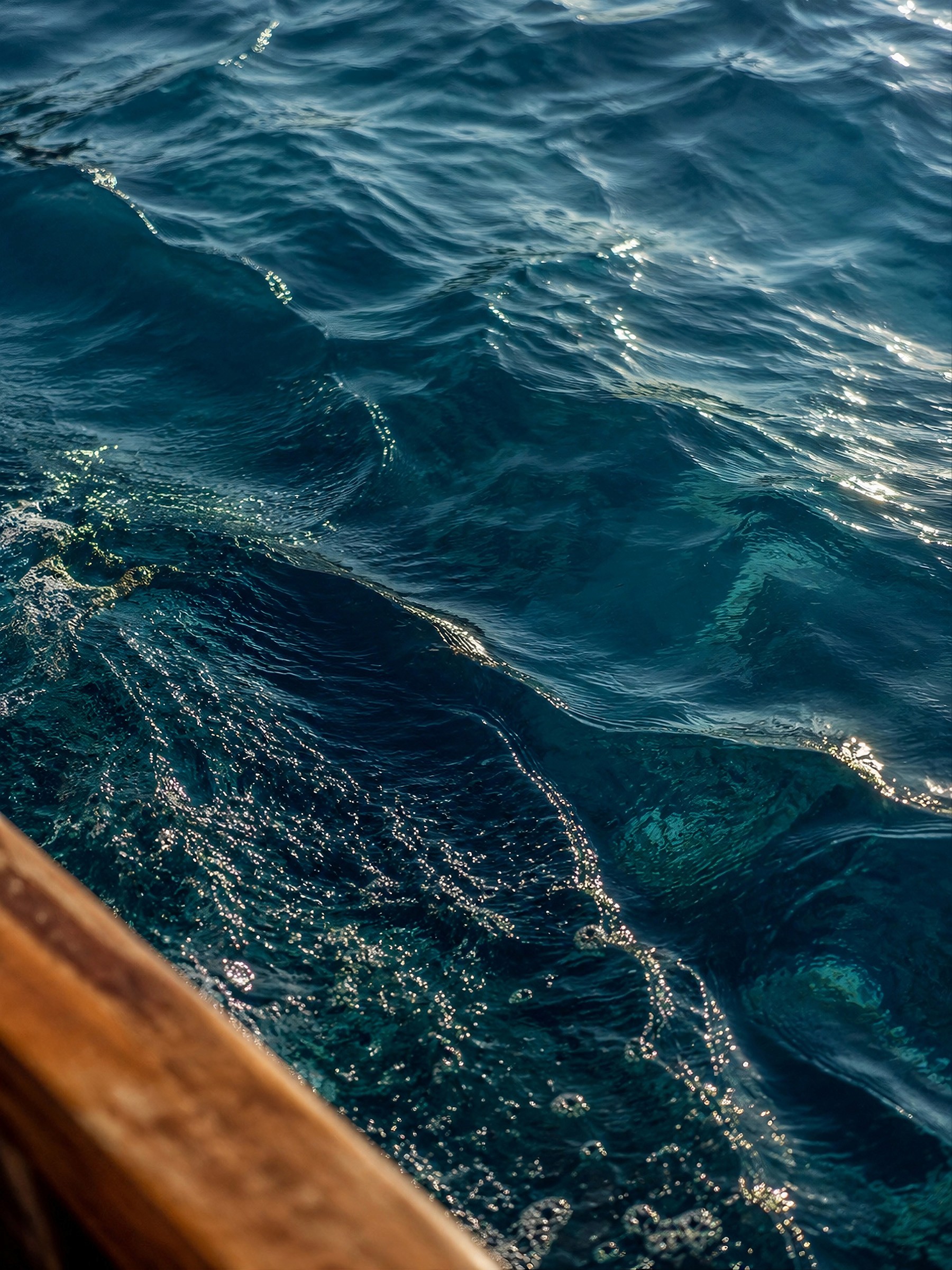 Close-up of dark blue sea waves next to the side of a wooden boat.
