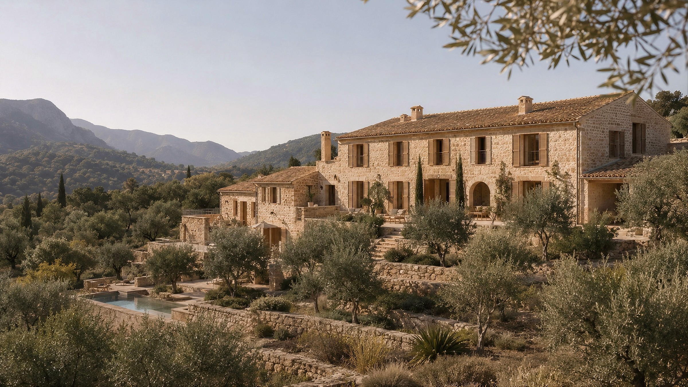 Large traditional stone villa with multi-level terraces, a pool, and an olive grove against a backdrop of rolling hills.